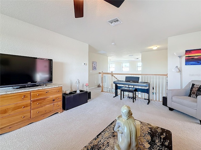 living room with ceiling fan, light colored carpet, and a textured ceiling