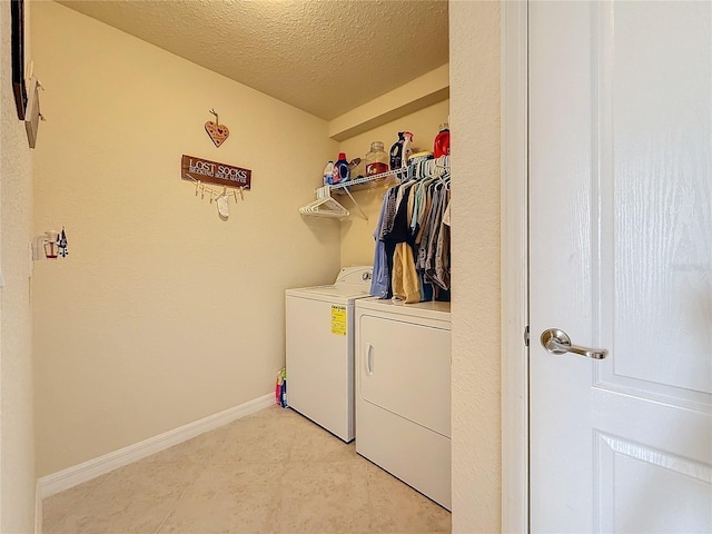 clothes washing area with washing machine and dryer and a textured ceiling