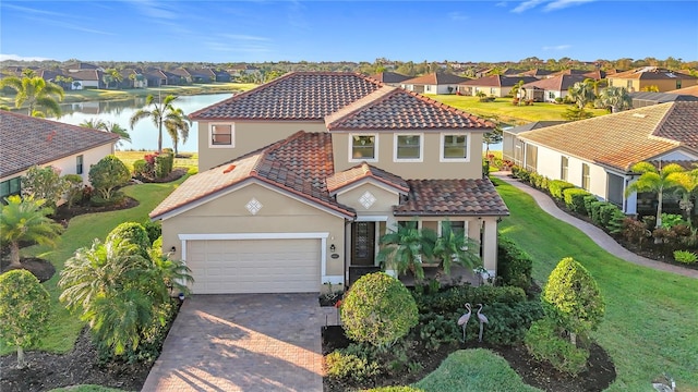 mediterranean / spanish house with a garage, a front yard, and a water view