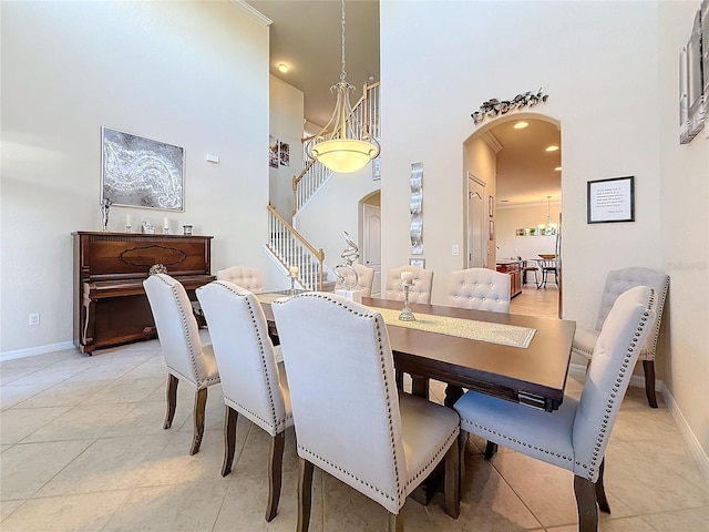 dining room with arched walkways, a high ceiling, baseboards, light tile patterned flooring, and recessed lighting
