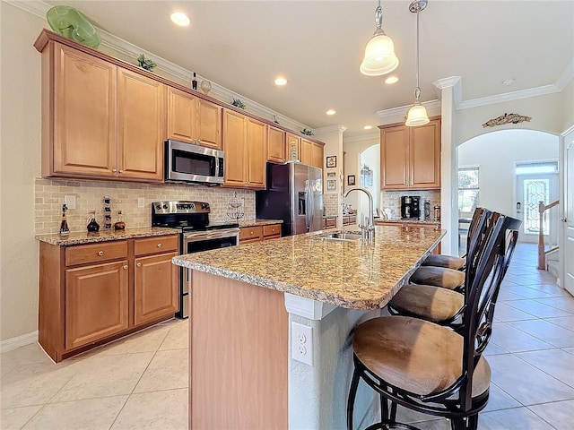 kitchen with appliances with stainless steel finishes, a sink, arched walkways, crown molding, and light stone countertops