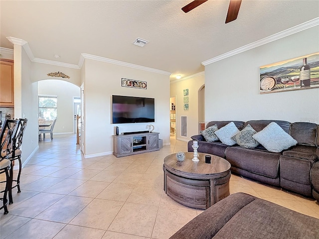 living area with arched walkways, light tile patterned floors, ceiling fan, ornamental molding, and baseboards