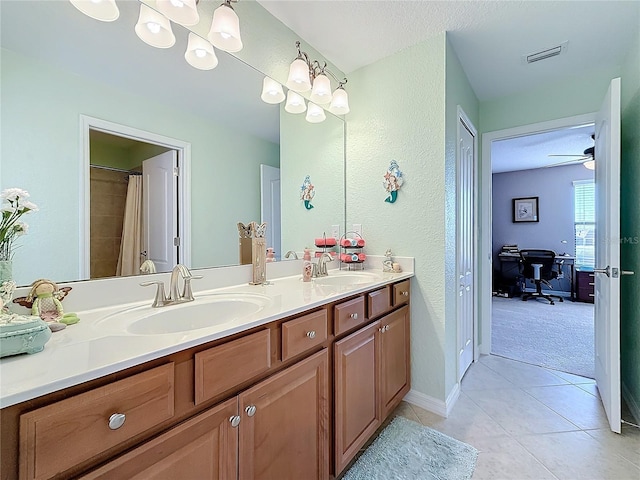 full bath with double vanity, tile patterned flooring, a textured wall, baseboards, and curtained shower