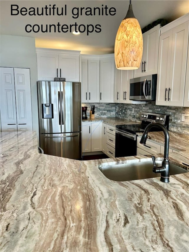 kitchen featuring white cabinetry, sink, pendant lighting, and stainless steel appliances