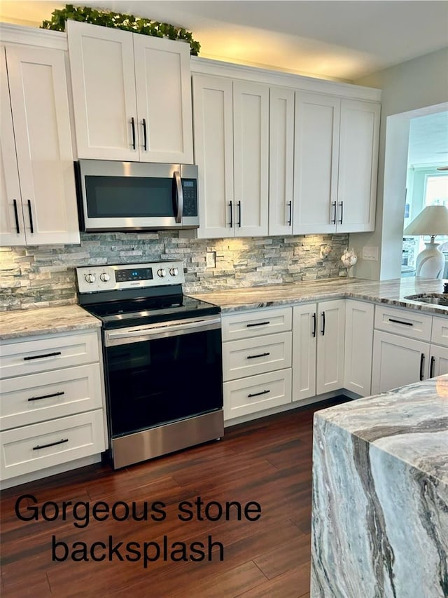 kitchen with white cabinetry, stainless steel appliances, light stone counters, and backsplash