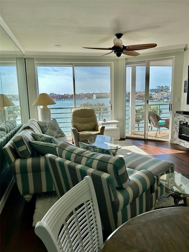 living room with a water view, a fireplace, dark hardwood / wood-style flooring, and crown molding