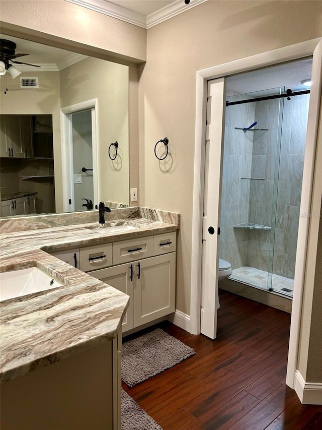 bathroom with crown molding, hardwood / wood-style flooring, vanity, a shower with shower door, and toilet