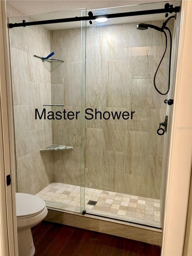 bathroom featuring walk in shower, toilet, and hardwood / wood-style floors