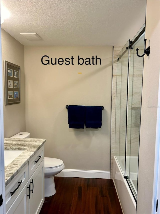 full bathroom with enclosed tub / shower combo, vanity, wood-type flooring, a textured ceiling, and toilet