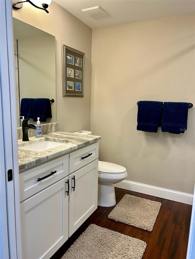 bathroom with vanity, a textured ceiling, wood-type flooring, and toilet