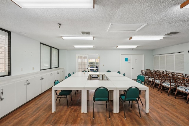 dining space with a textured ceiling and dark hardwood / wood-style flooring