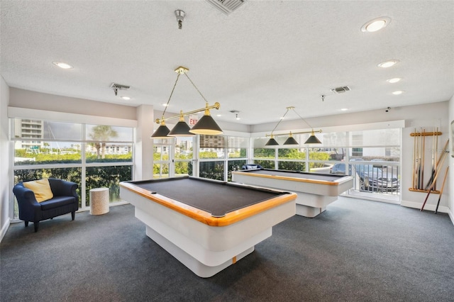 game room with plenty of natural light, a textured ceiling, and dark colored carpet