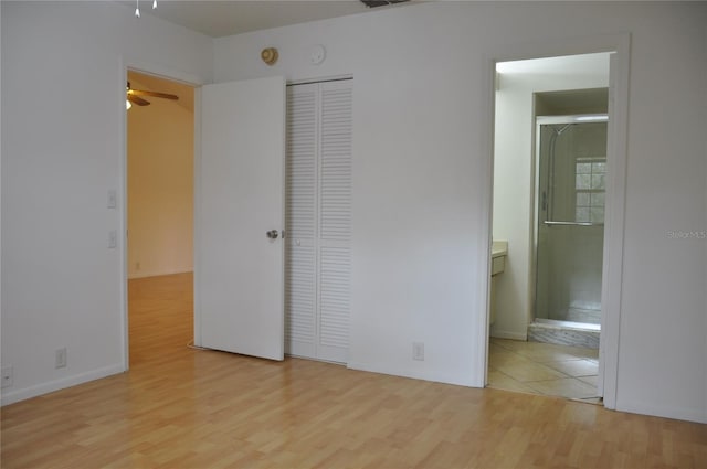 unfurnished bedroom with connected bathroom, a closet, and light wood-type flooring