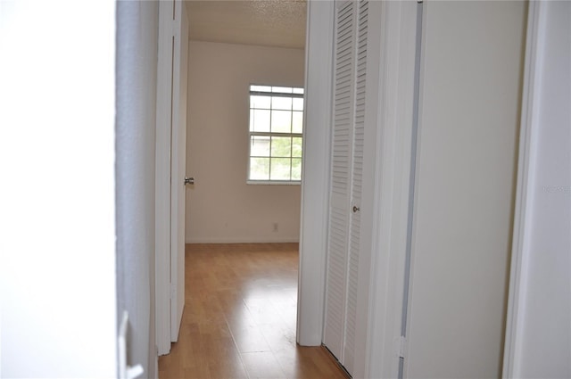 hall featuring a textured ceiling and light wood-type flooring