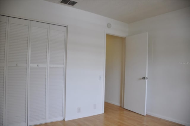 unfurnished bedroom with light wood-type flooring and a closet