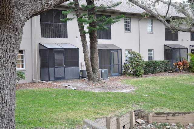 rear view of property with a sunroom, a yard, and central air condition unit