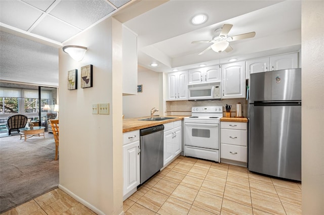 kitchen with stainless steel appliances, sink, white cabinets, and butcher block countertops