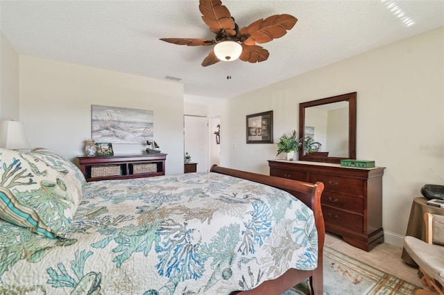 bedroom featuring ceiling fan, a textured ceiling, and light tile patterned floors