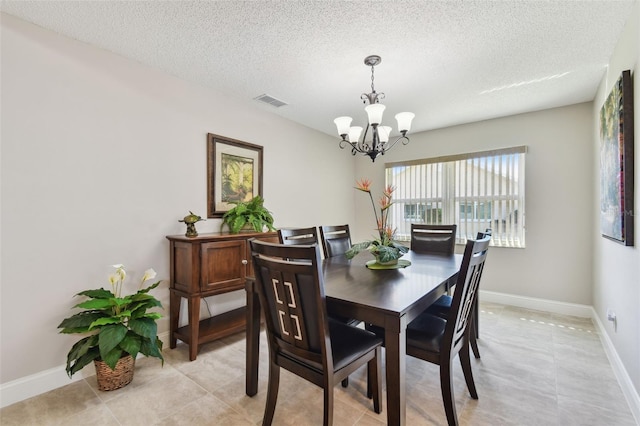 dining area with a notable chandelier, a textured ceiling, and light tile patterned flooring