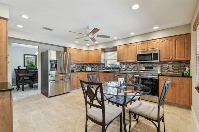 kitchen with appliances with stainless steel finishes, sink, backsplash, and ceiling fan