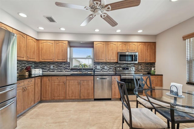 kitchen featuring light tile patterned flooring, sink, dark stone countertops, appliances with stainless steel finishes, and backsplash