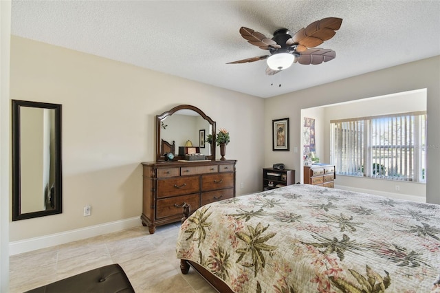 bedroom featuring ceiling fan, light tile patterned floors, and a textured ceiling