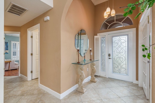 foyer entrance with light tile patterned floors and an inviting chandelier