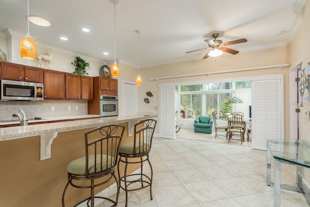 kitchen with tasteful backsplash, appliances with stainless steel finishes, a kitchen bar, and decorative light fixtures