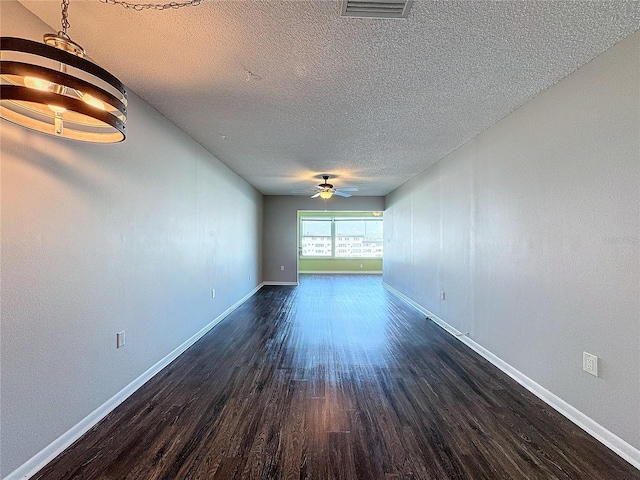 empty room featuring ceiling fan, a textured ceiling, and dark hardwood / wood-style flooring