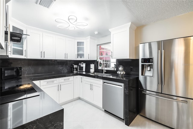 kitchen featuring light tile patterned flooring, appliances with stainless steel finishes, sink, white cabinets, and backsplash