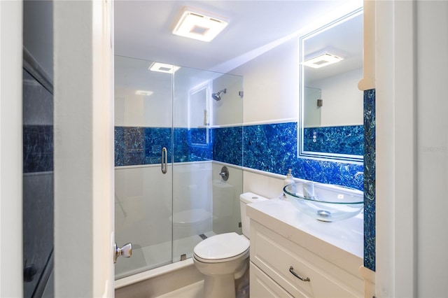 bathroom with walk in shower, tile walls, vanity, and toilet