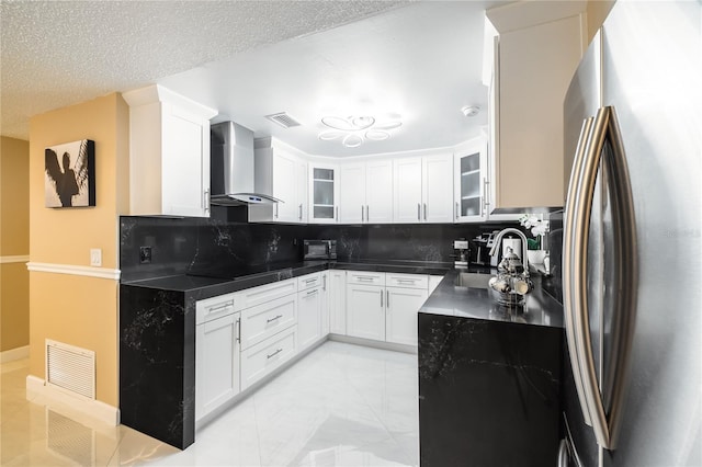 kitchen featuring wall chimney range hood, stainless steel fridge, sink, and white cabinets