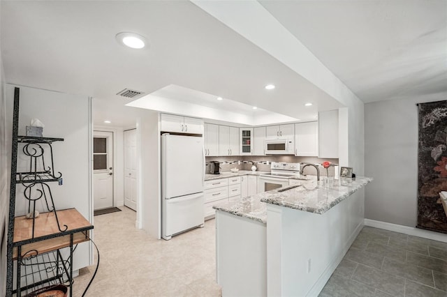 kitchen featuring sink, white cabinets, light stone counters, kitchen peninsula, and white appliances