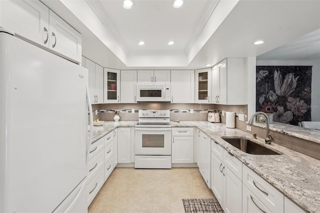 kitchen with white appliances, a tray ceiling, sink, and white cabinets