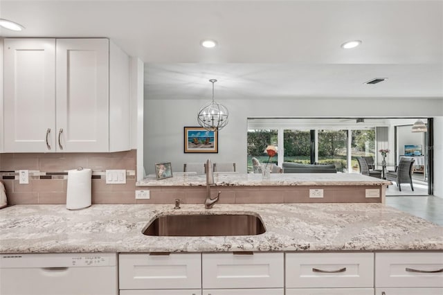 kitchen with sink, dishwasher, hanging light fixtures, light stone countertops, and white cabinets