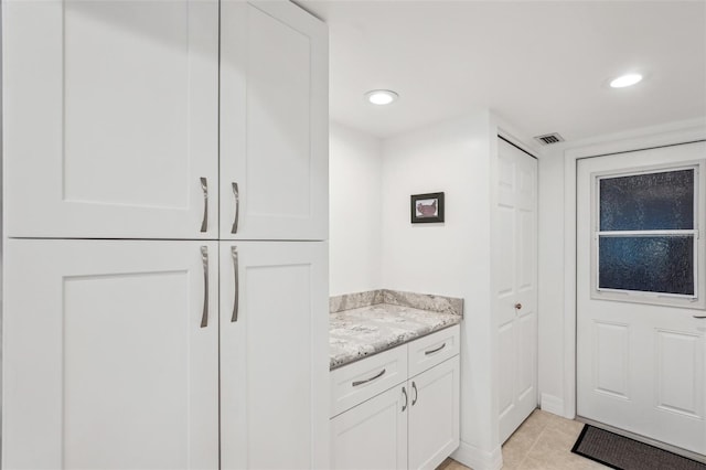 kitchen featuring light stone countertops, light tile patterned floors, and white cabinets