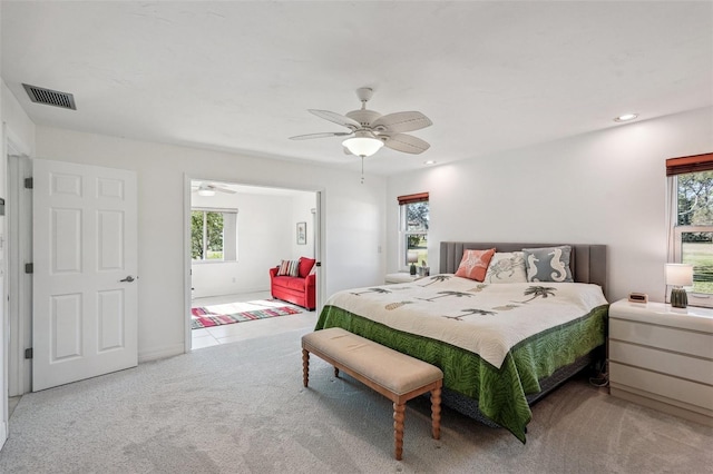 carpeted bedroom featuring multiple windows and ceiling fan