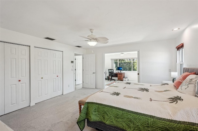 carpeted bedroom with ceiling fan and multiple closets