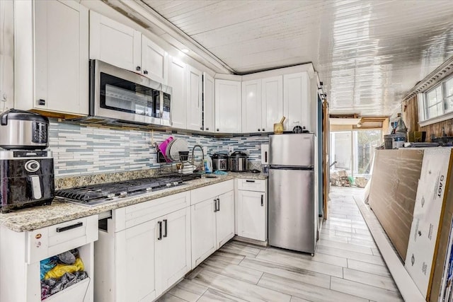 kitchen featuring white cabinetry, decorative backsplash, light stone countertops, and appliances with stainless steel finishes