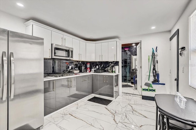 kitchen with tasteful backsplash, a breakfast bar, white cabinets, and appliances with stainless steel finishes