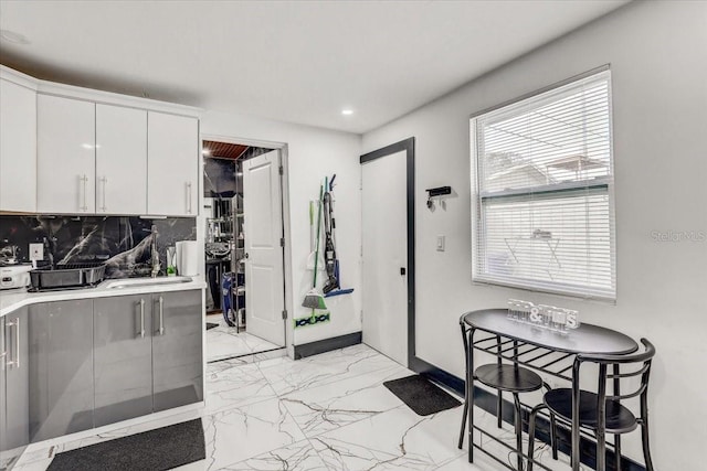 kitchen with tasteful backsplash and white cabinets