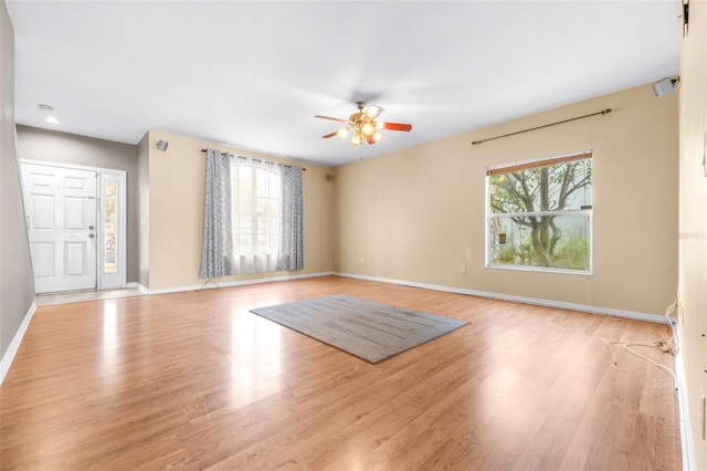 empty room featuring ceiling fan, plenty of natural light, and light hardwood / wood-style flooring