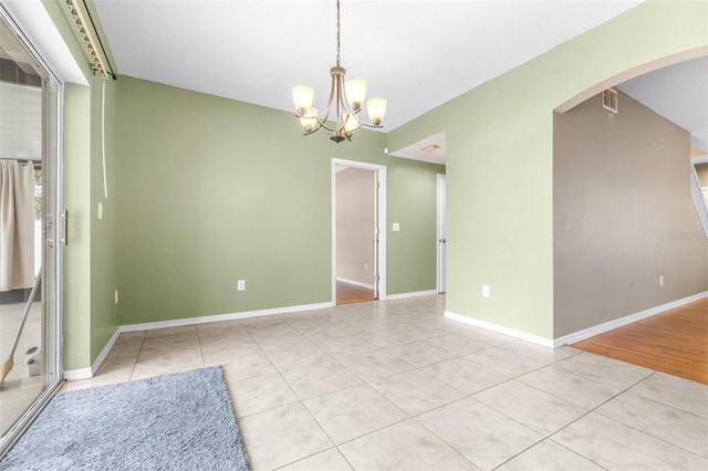 tiled empty room with an inviting chandelier