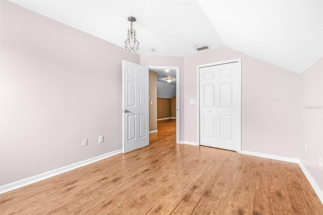 unfurnished bedroom featuring vaulted ceiling, light hardwood / wood-style floors, and a closet