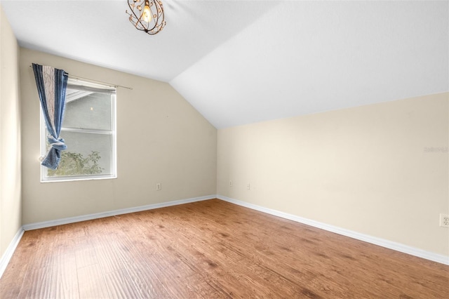 additional living space featuring wood-type flooring and vaulted ceiling