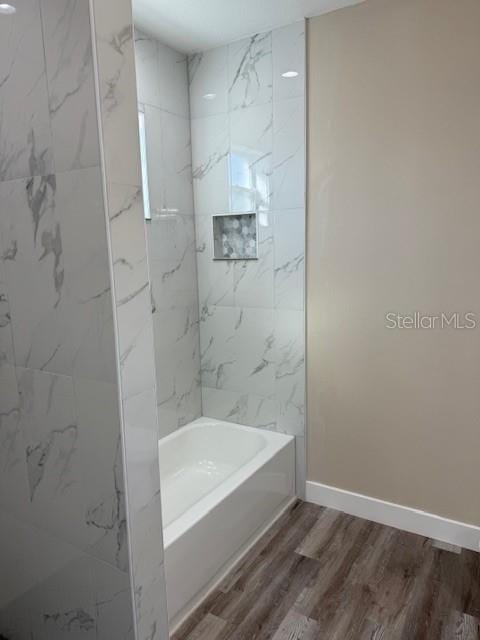 bathroom featuring tiled shower / bath combo and wood-type flooring