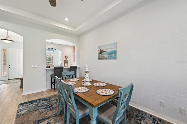 dining room featuring hardwood / wood-style flooring, a raised ceiling, and ceiling fan