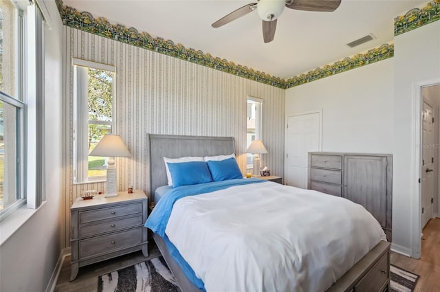 bedroom with ceiling fan, hardwood / wood-style floors, and multiple windows