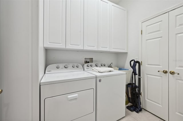 laundry room featuring cabinets, light tile patterned floors, and washing machine and clothes dryer