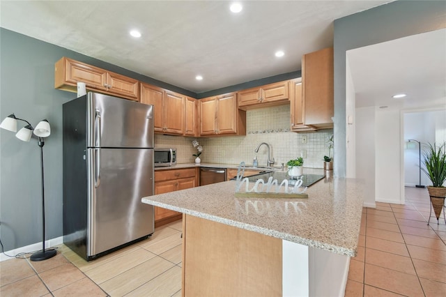 kitchen with tasteful backsplash, appliances with stainless steel finishes, light stone countertops, and kitchen peninsula